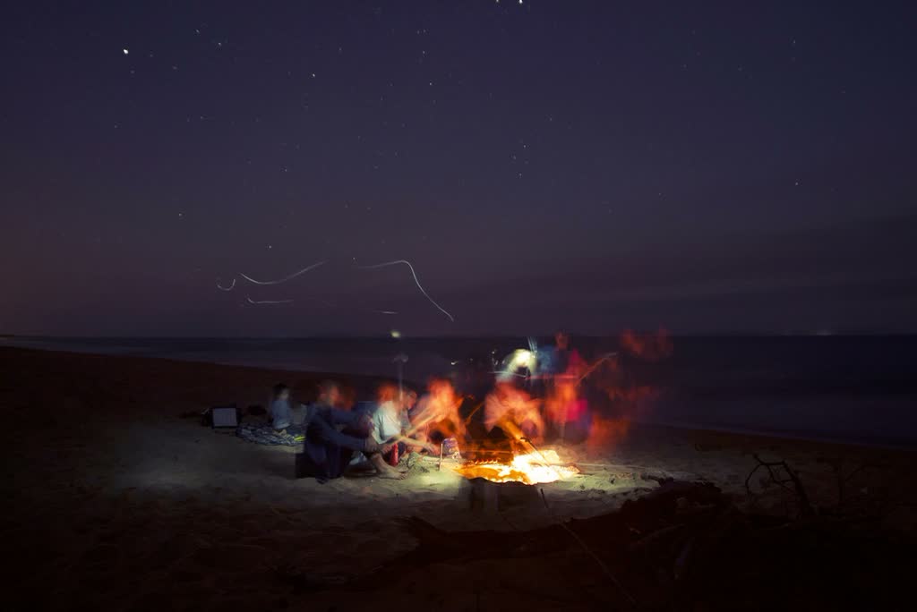 Friends around a beach bonfire at night